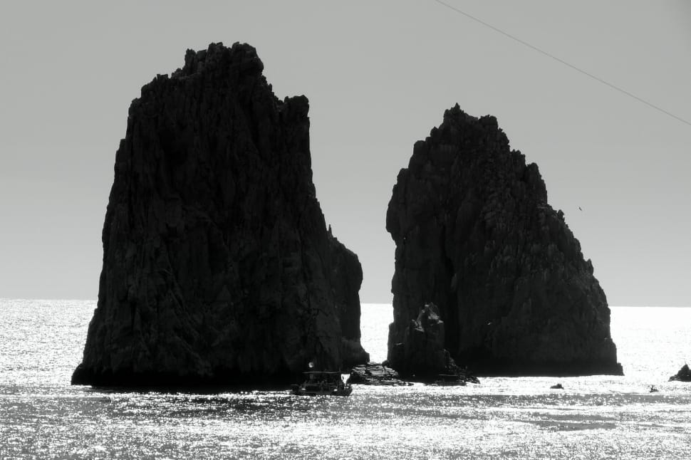landscape grayscale photography of two islet and boat during daytime preview