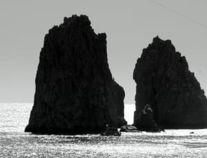 landscape grayscale photography of two islet and boat during daytime thumbnail