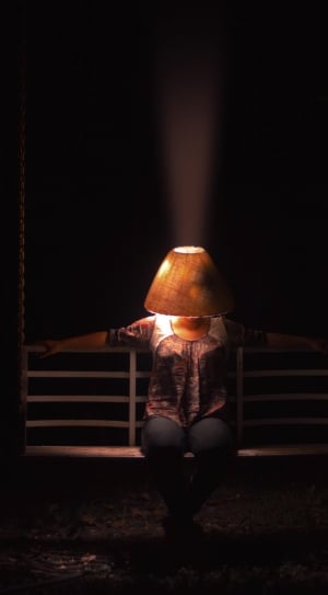 woman in brown and gray scoop neck t-shirt and gray pants sitting on bench with lamp on her head thumbnail