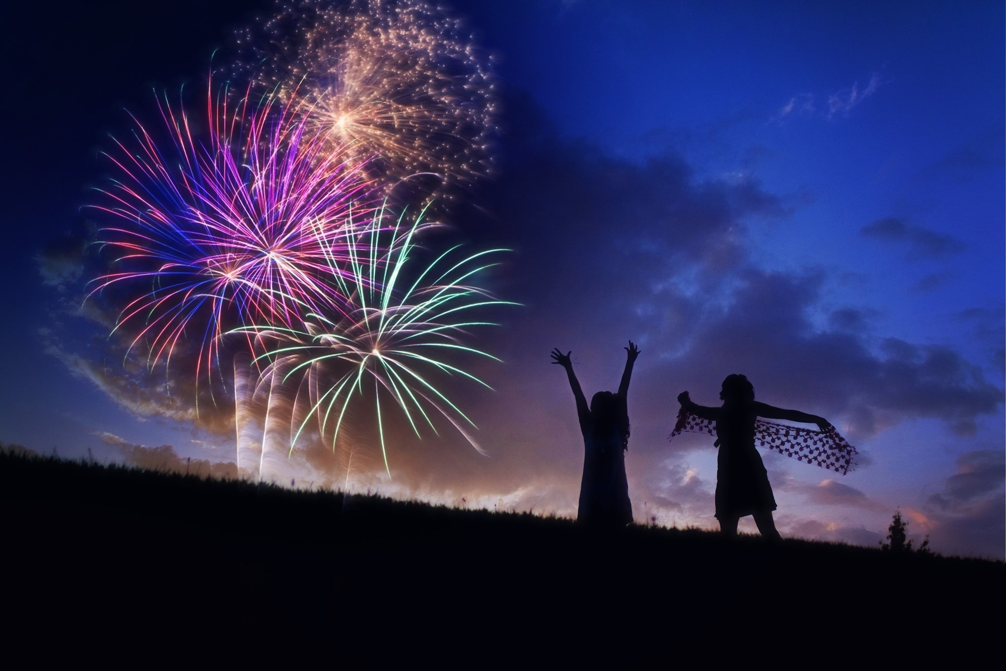 silhouette of two girls watching fireworks
