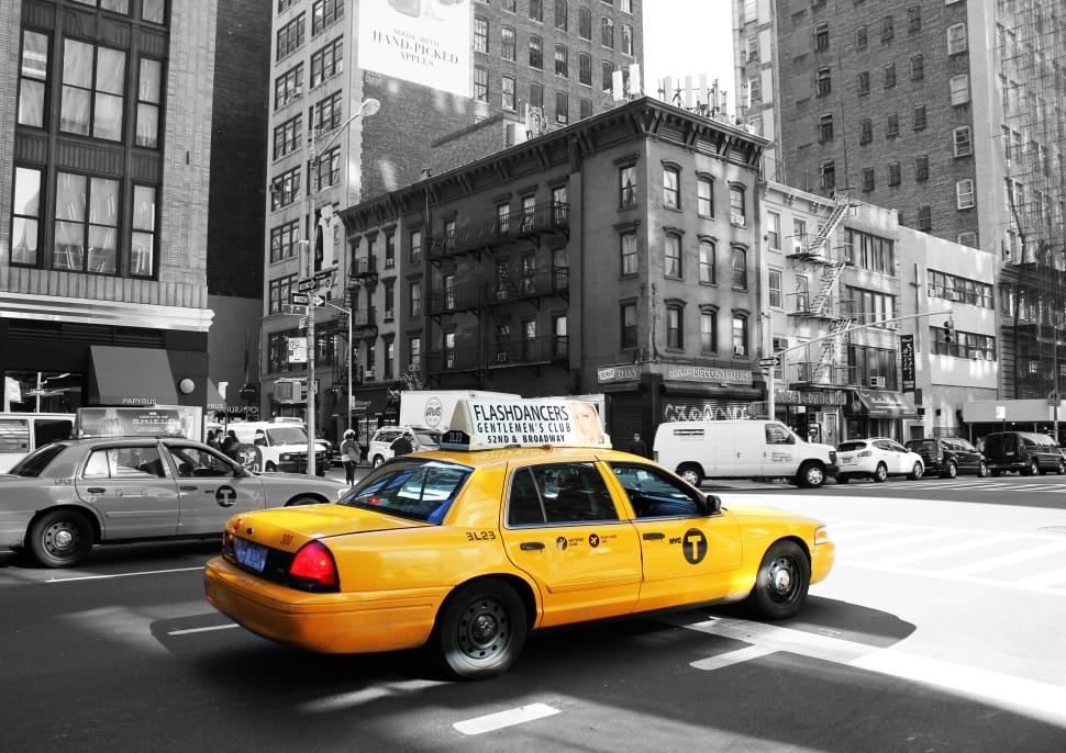 yellow sedan beside gray sedan surrounded by buildings preview