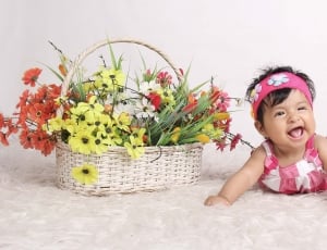 baby in pink and white dress beside basket of cosmos flower thumbnail