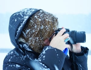 person wearing black snow jacket holding black bridge camera thumbnail