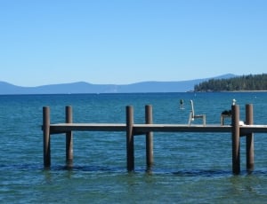 white and brown wooden dock near body of water under blue sky during daytime thumbnail