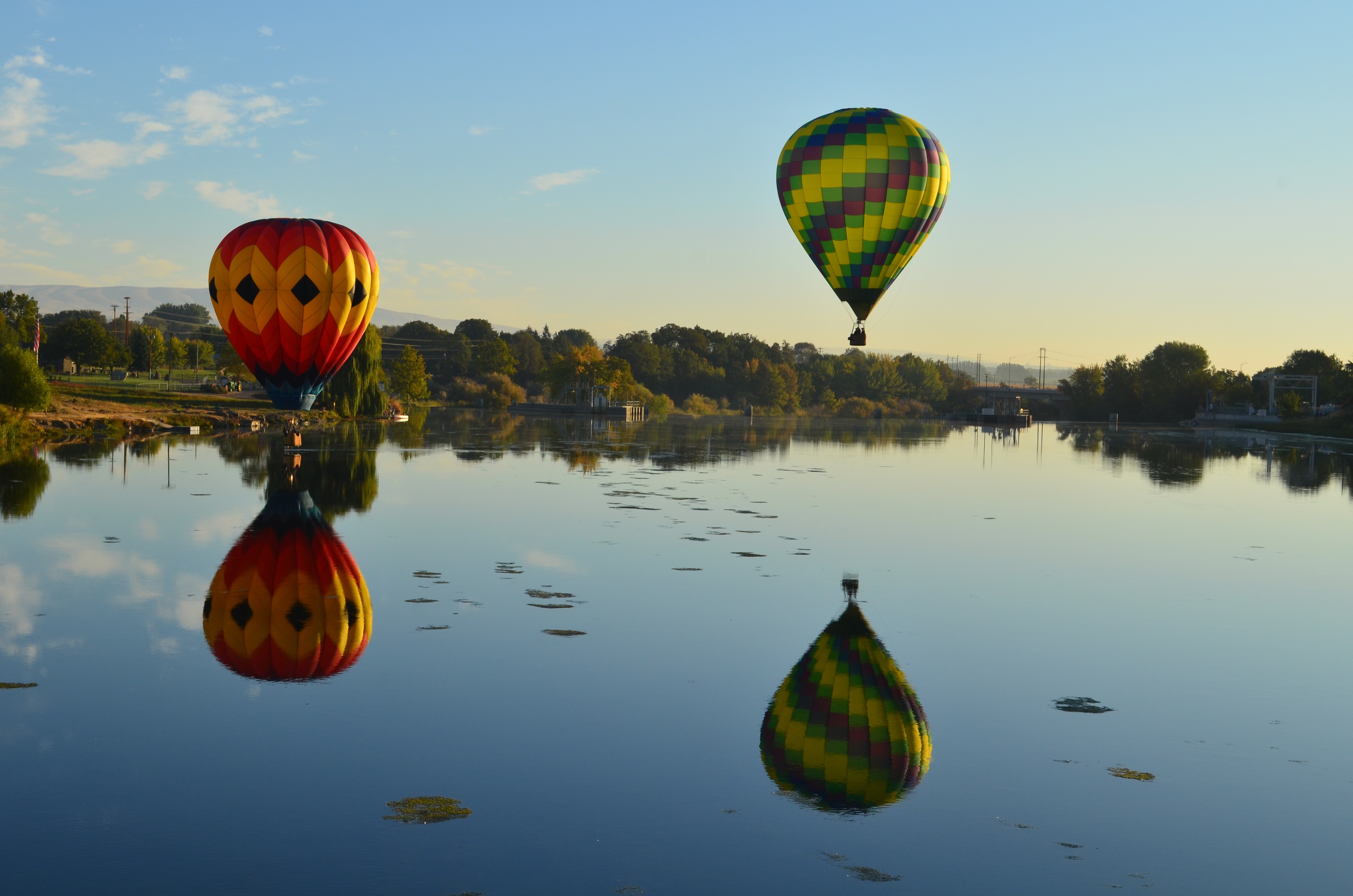 two hot air balloons floating above body of water under clear sky during daytime