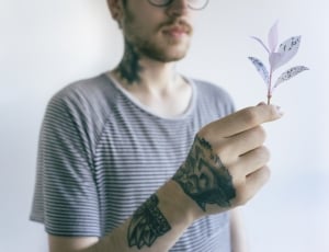 man in black and white shirt holding pink leaves plant thumbnail