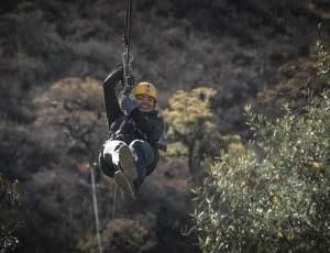 person ride on zip line during day time thumbnail