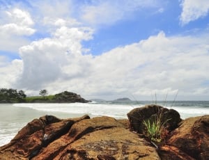 brown rock formations beside ocean under cloudy sky during daytime thumbnail