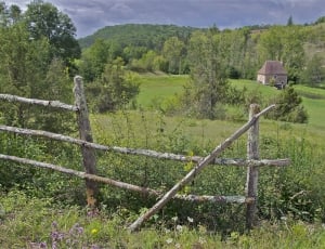 brown wooden fence with house in the middle of green trees thumbnail
