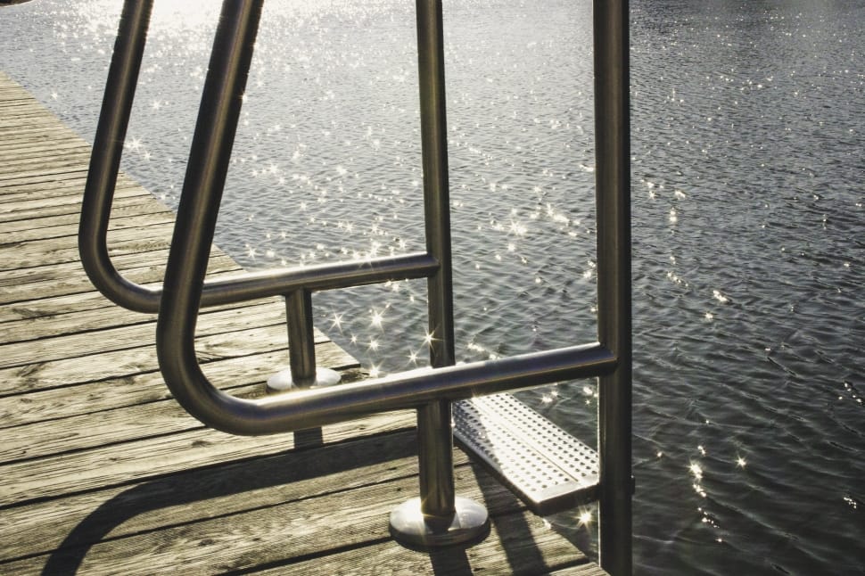 gray metal ladder on brown wooden sea dock near body of water preview