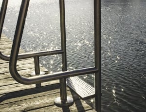 gray metal ladder on brown wooden sea dock near body of water thumbnail