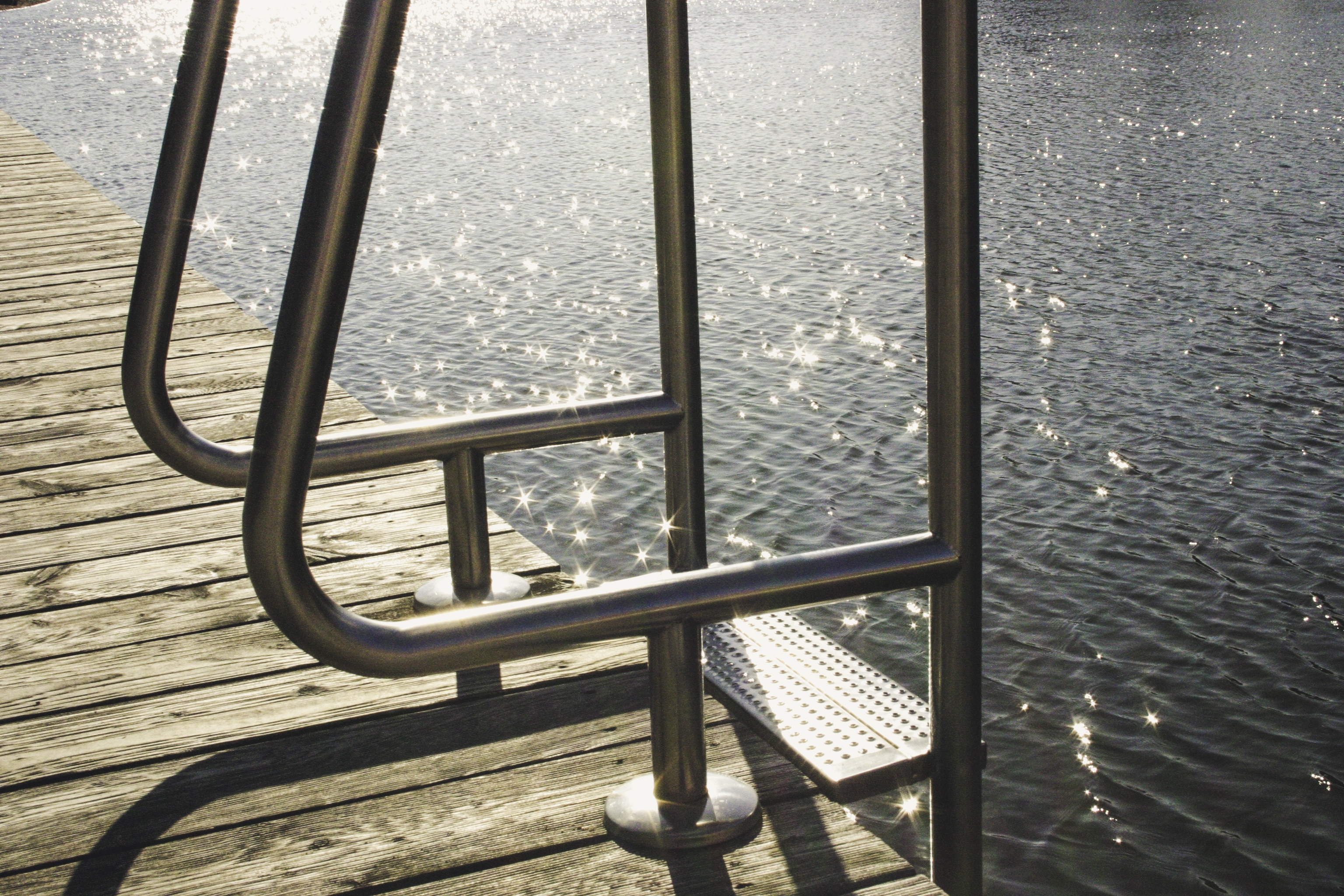 gray metal ladder on brown wooden sea dock near body of water
