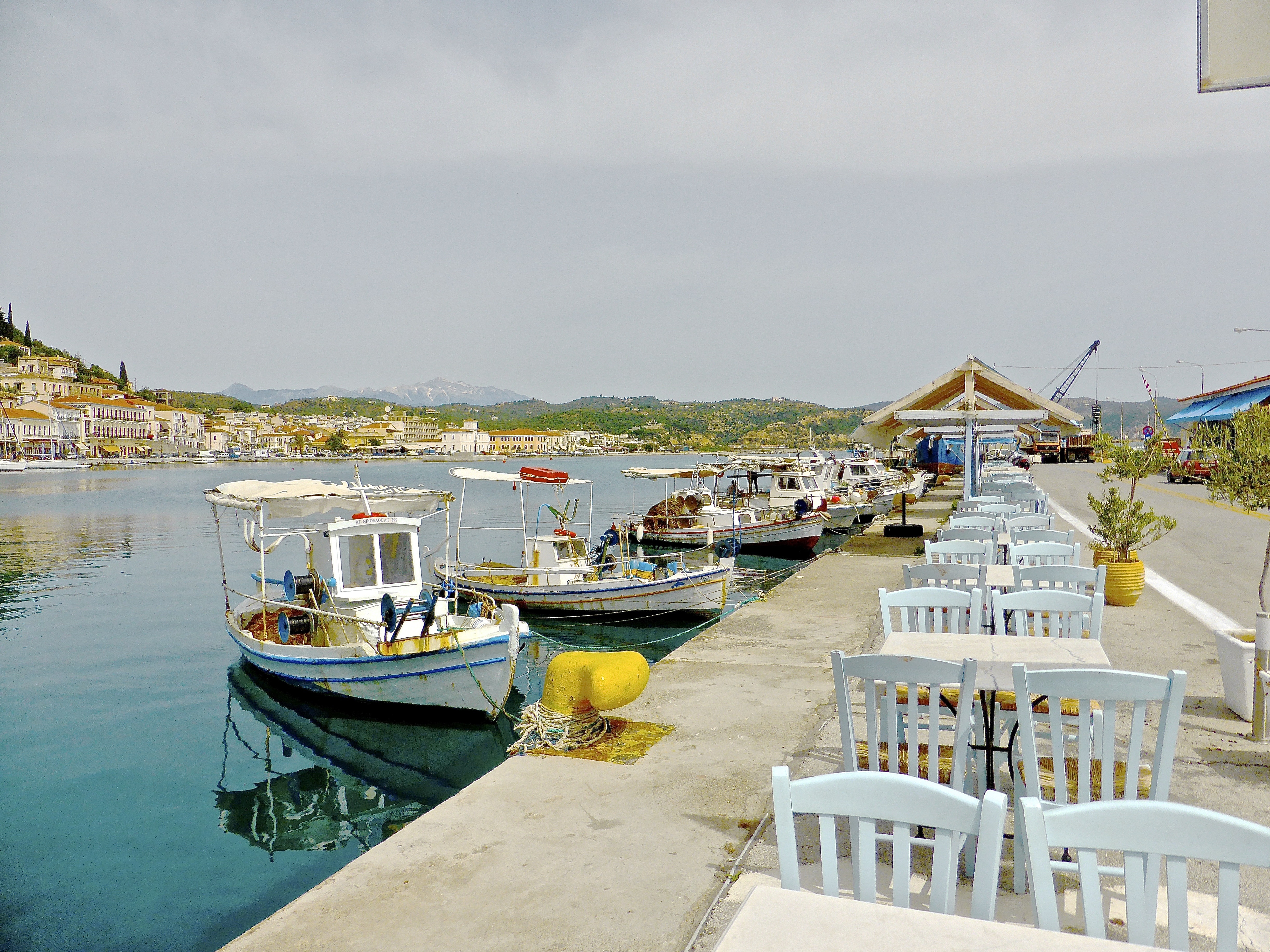 body of water with boat and white chairs during day time