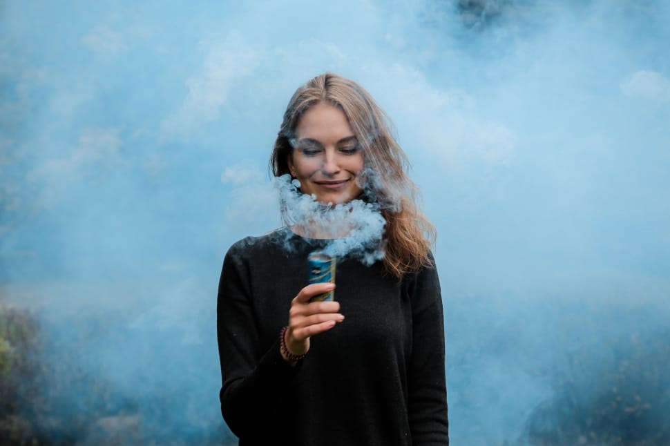 woman in black sweater holding blue smoke bomb preview