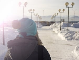 woman wearing blue and brown bobble hat and black hooded jacket thumbnail