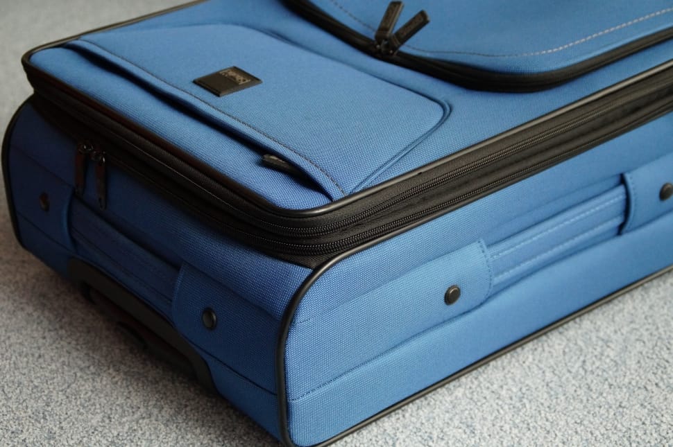blue luggage bag on top of gray surface preview