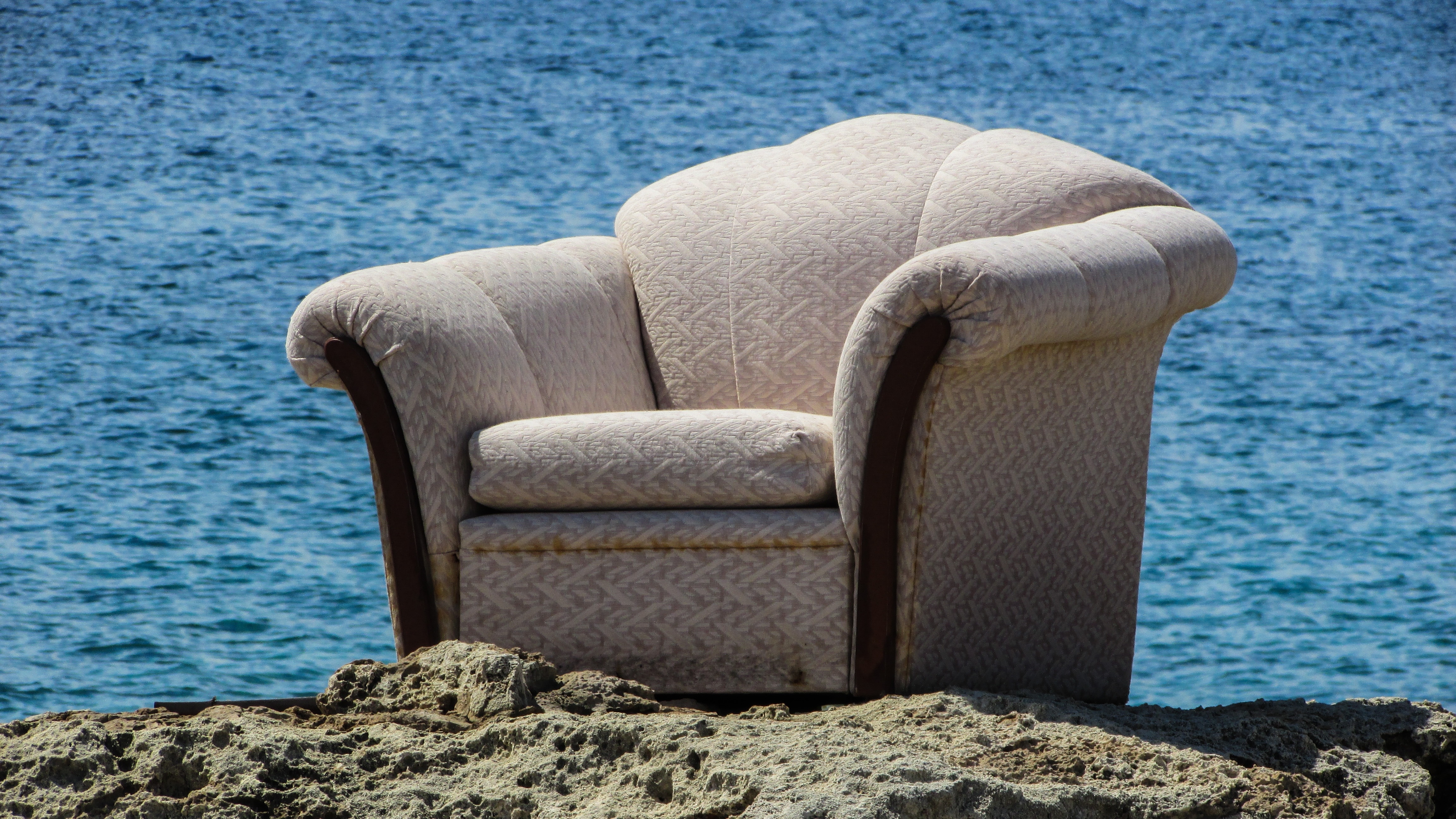 gray sofa chair at the sand dunes near body of water