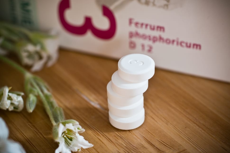 five stacked round white medicinal pills beside white petaled flower preview