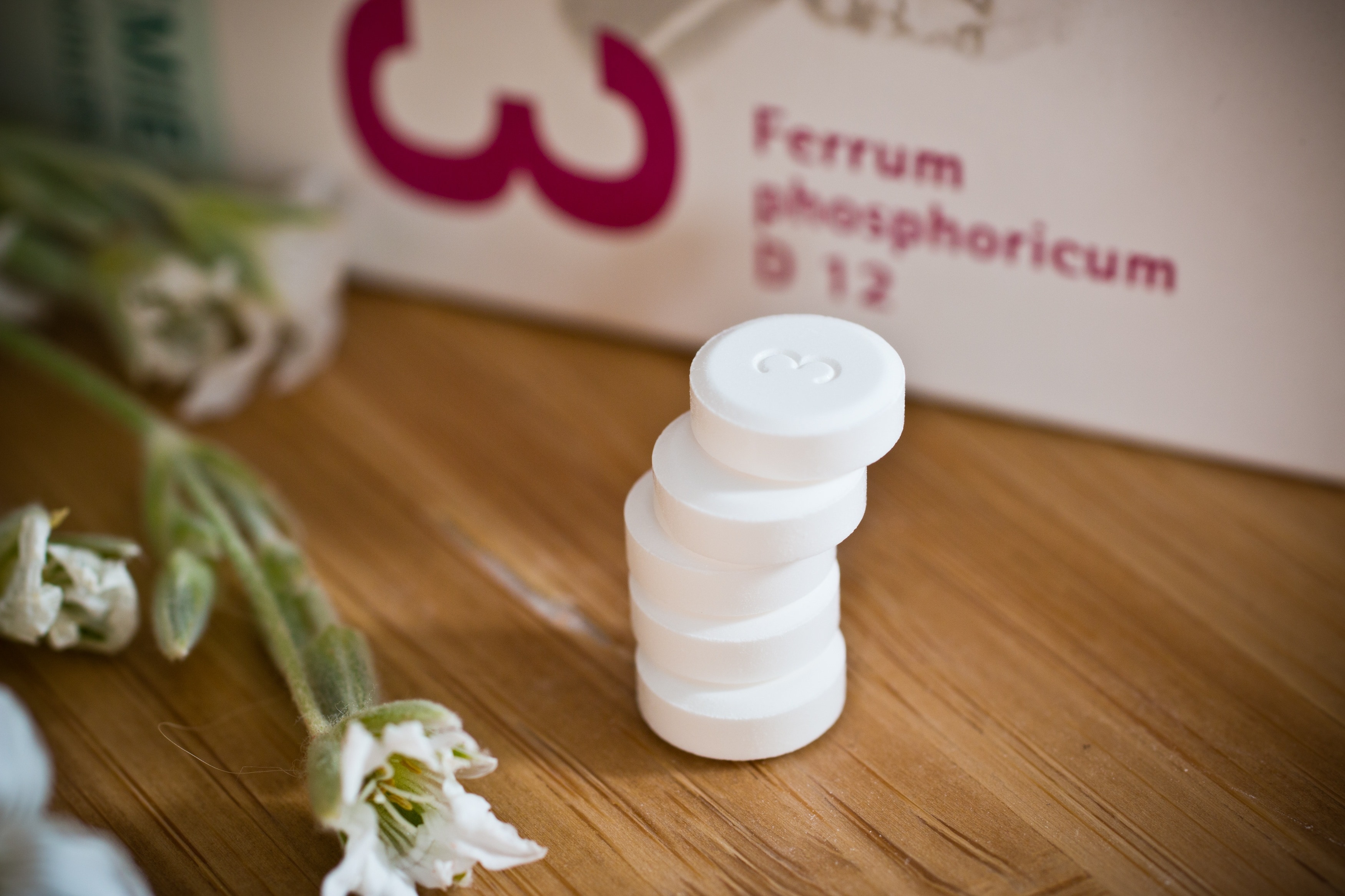 five stacked round white medicinal pills beside white petaled flower