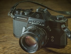 Black Pentax Digital Camera on Brown Surface thumbnail