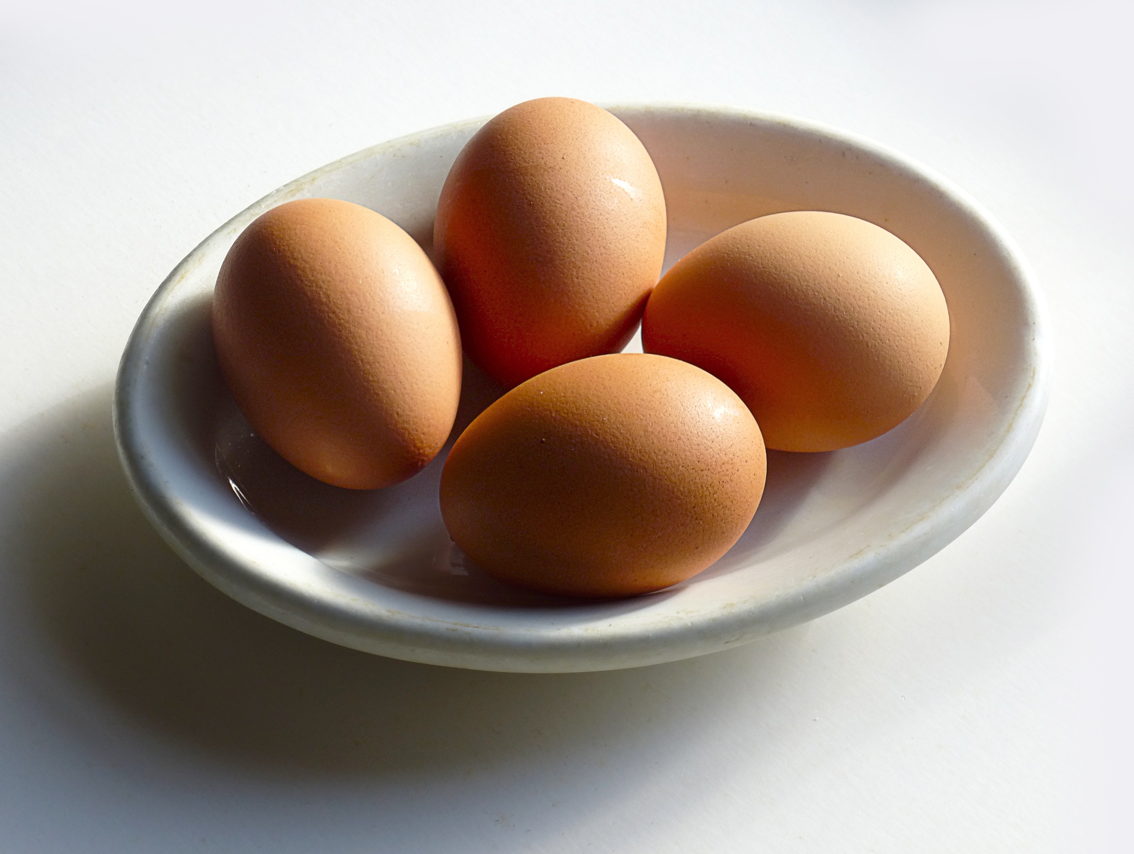 4 brown chicken eggs on white ceramic saucer