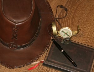 brown leather cowboy hat and gold round compass and black flick pen thumbnail
