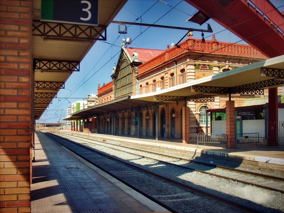 white and brown train station in front of railway during daytime preview