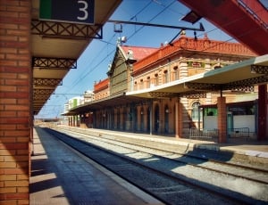 white and brown train station in front of railway during daytime thumbnail