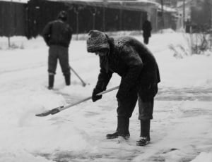 grayscale photography of man shoveling snow thumbnail