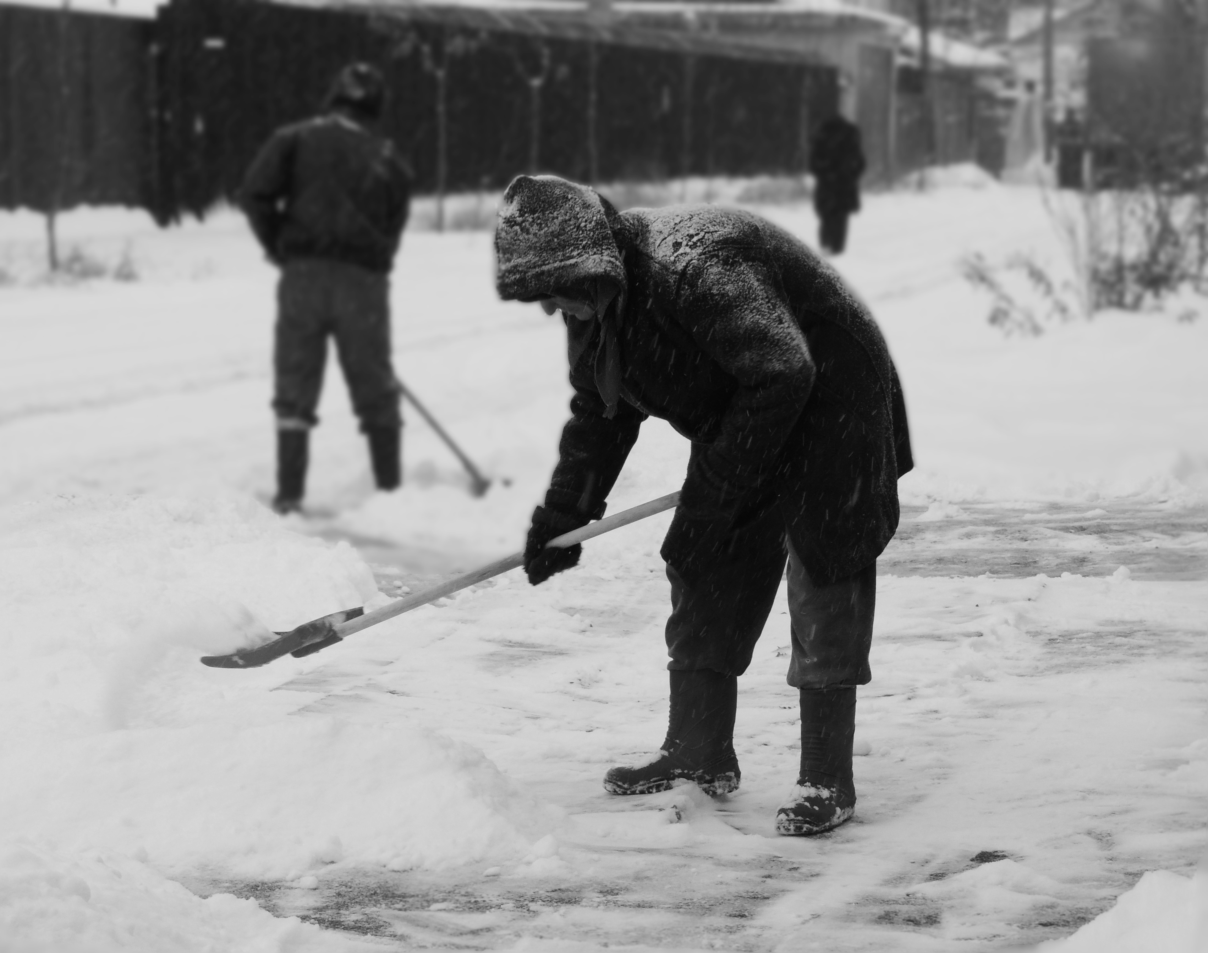 grayscale photography of man shoveling snow