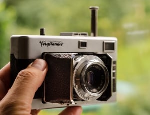 person holding white film camera thumbnail