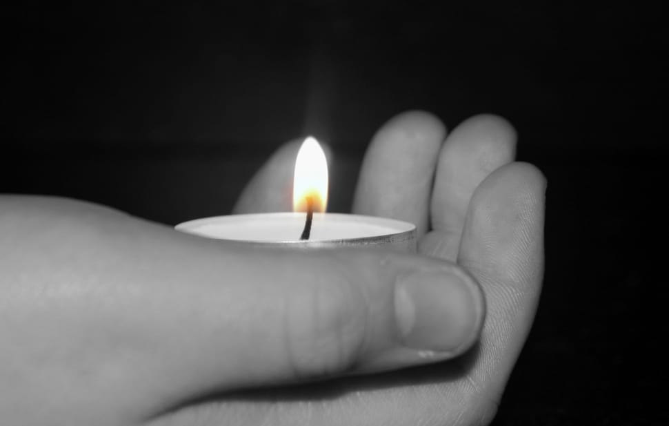 selective photo of human hand holding tealight candle preview