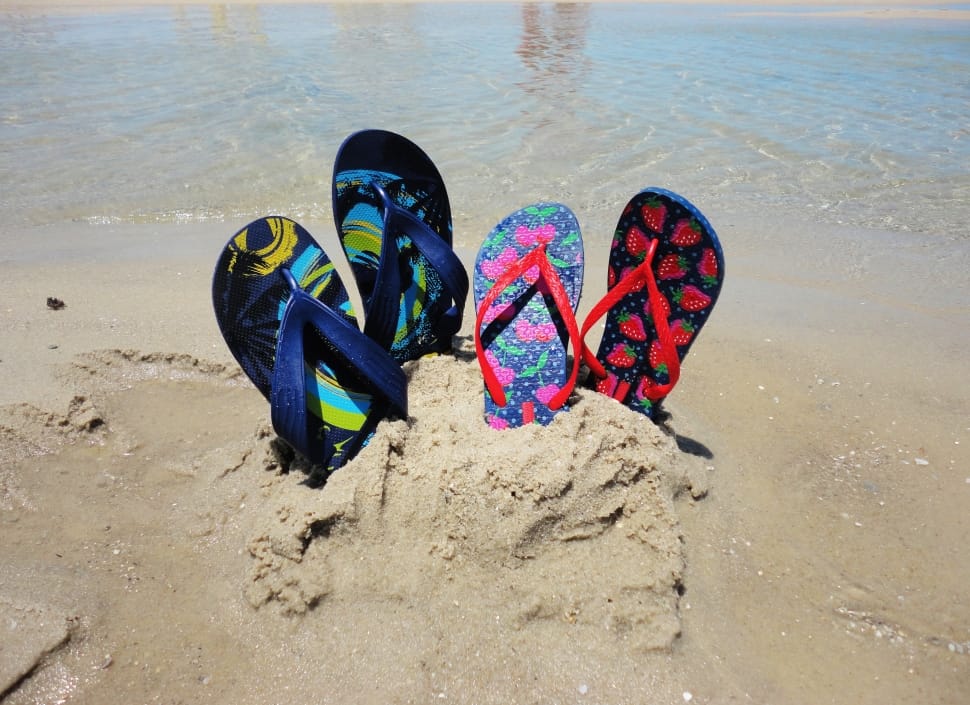 two pair of flip flops on the sand near water at daytime preview