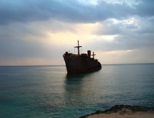 rusted gray ship on body of water under cloudy skyy thumbnail