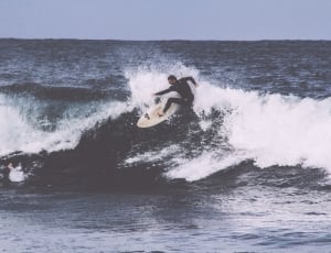 man in black wet suit surfing on ocean during daytime photo thumbnail