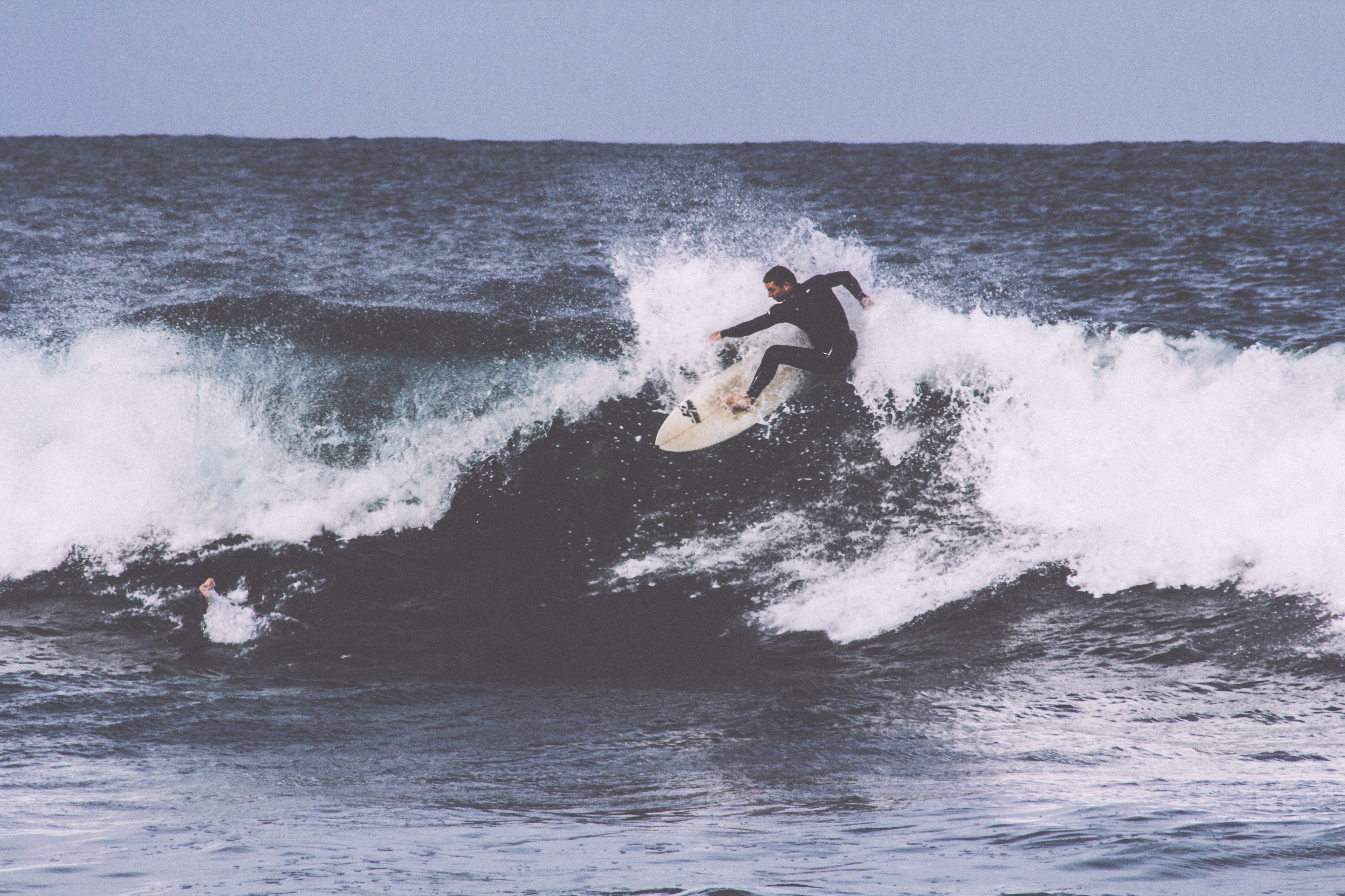 man in black wet suit surfing on ocean during daytime photo