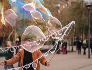 man forming bubbles using round frame during daytime thumbnail