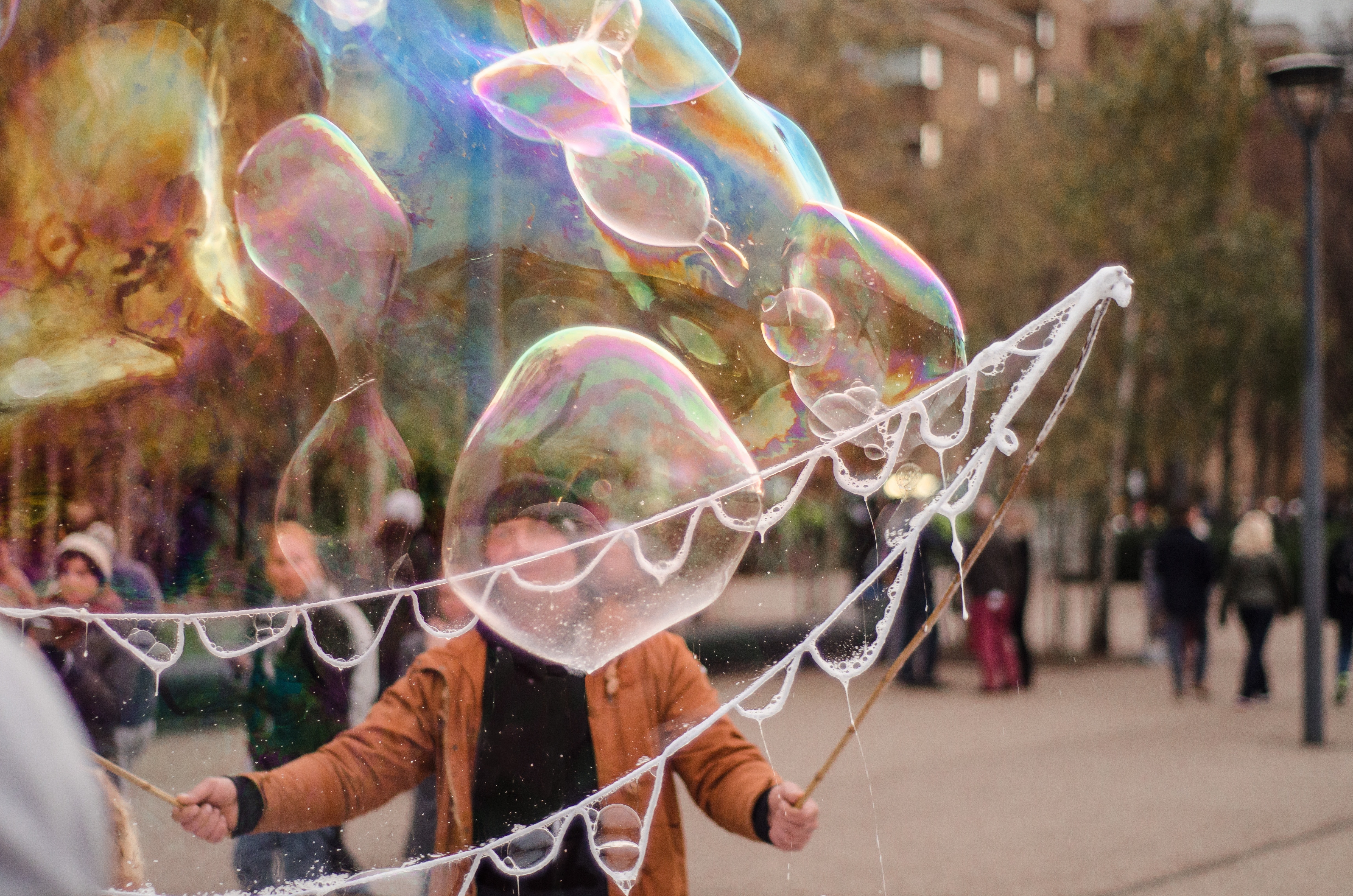 man forming bubbles using round frame during daytime