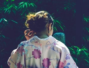 woman in floral dress touching her tied hair near garden thumbnail