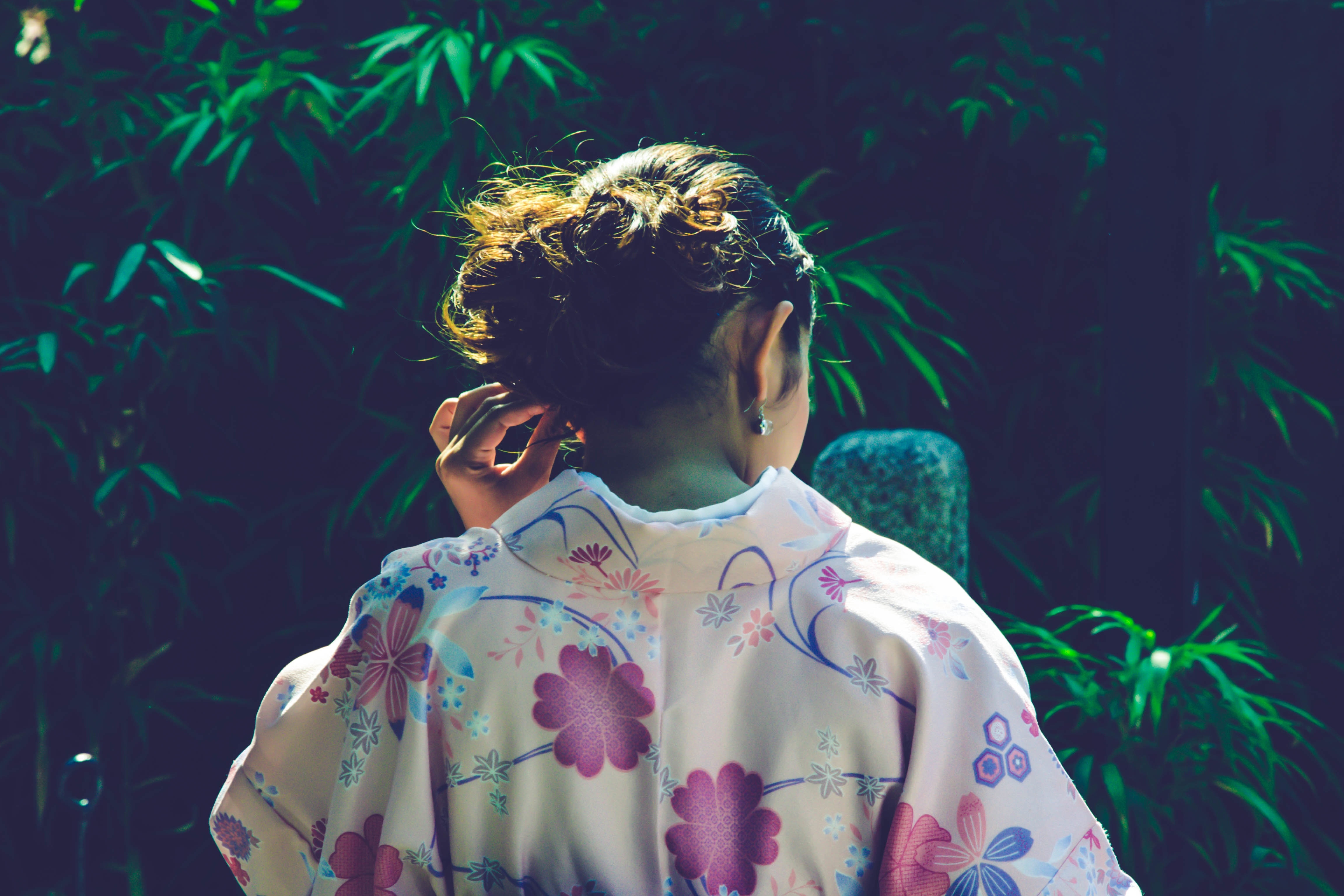 woman in floral dress touching her tied hair near garden