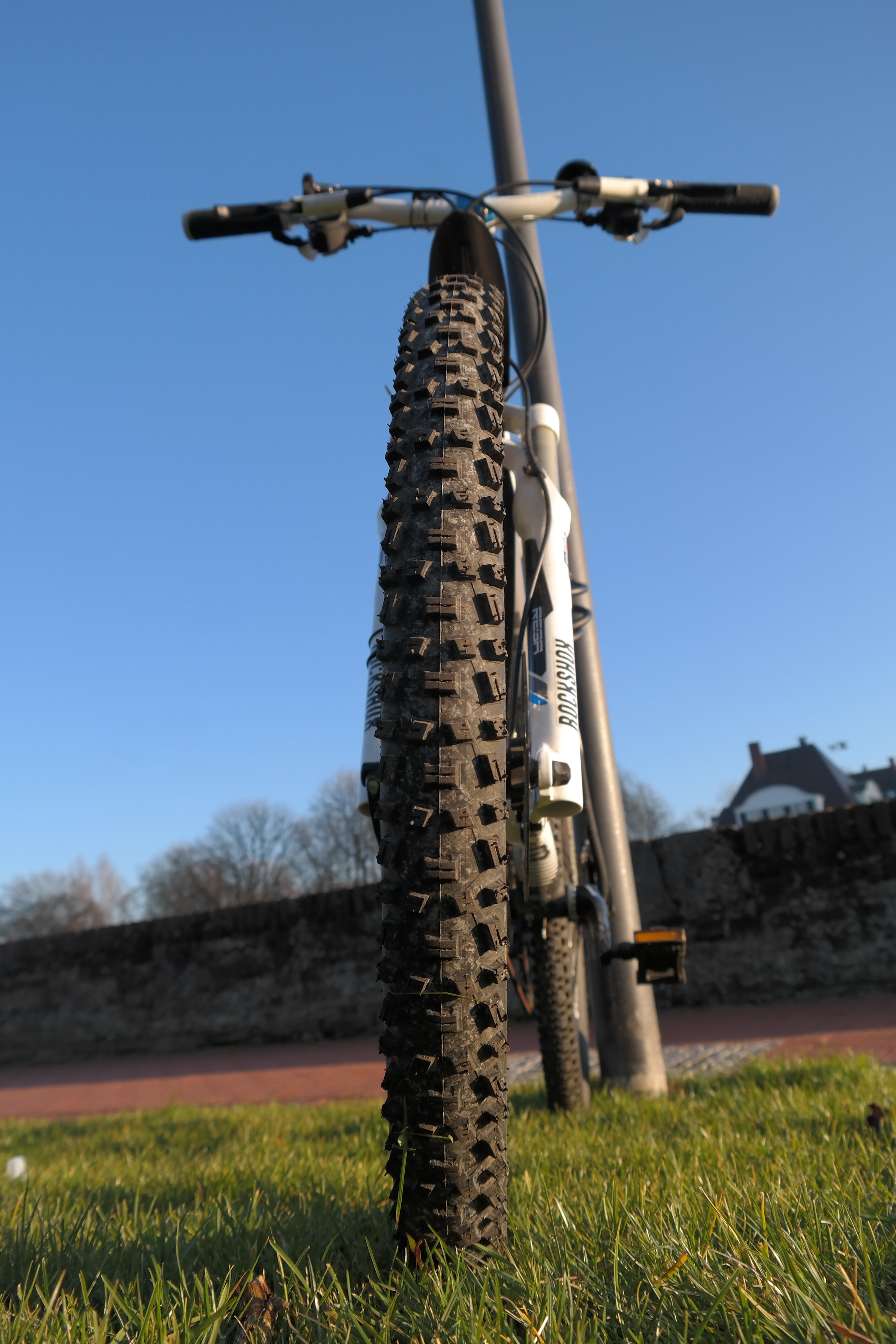 white hardtail mountain bike beside gray metal stand during daytime