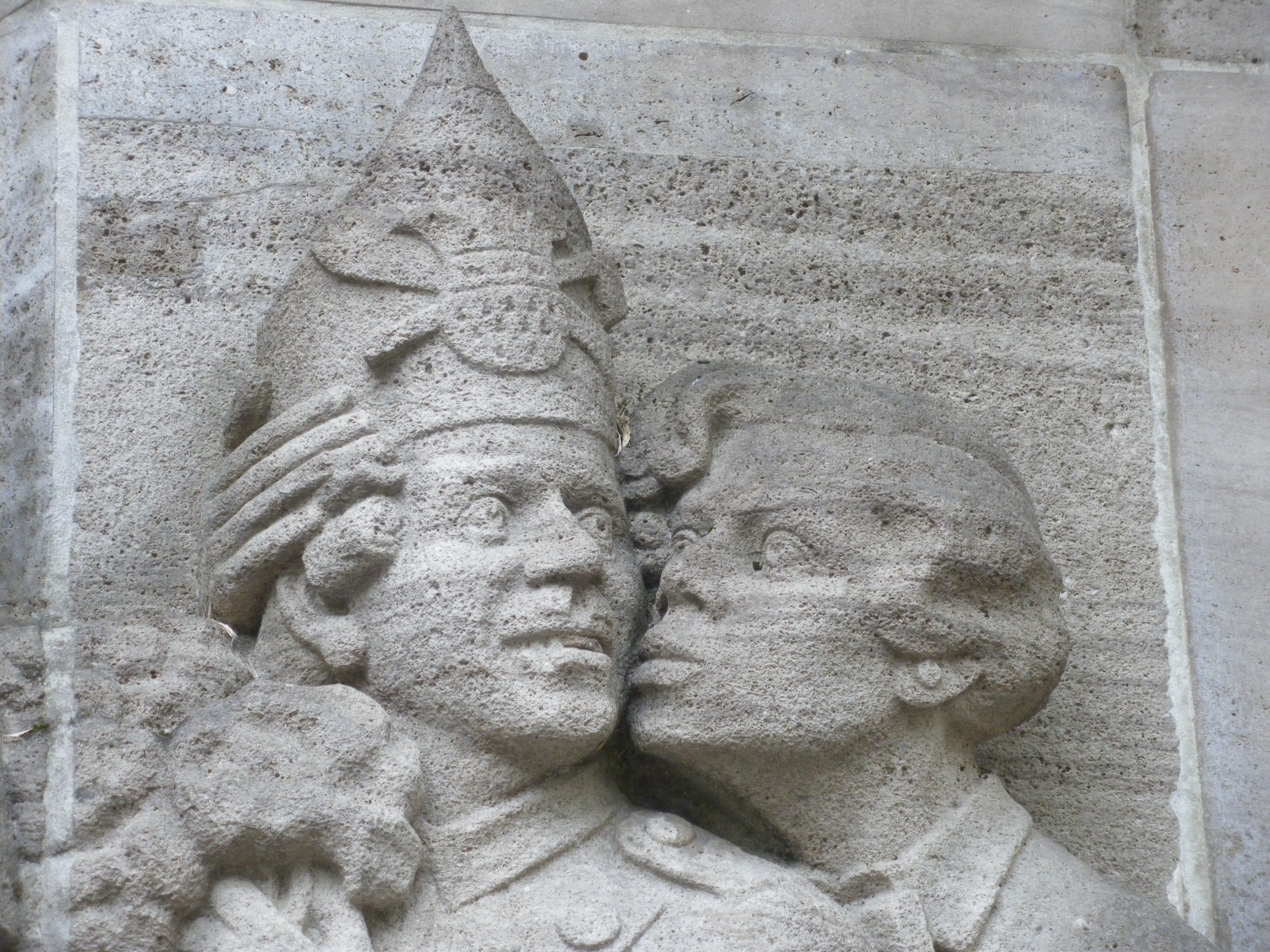 photo of woman kissing man wearing crown statue