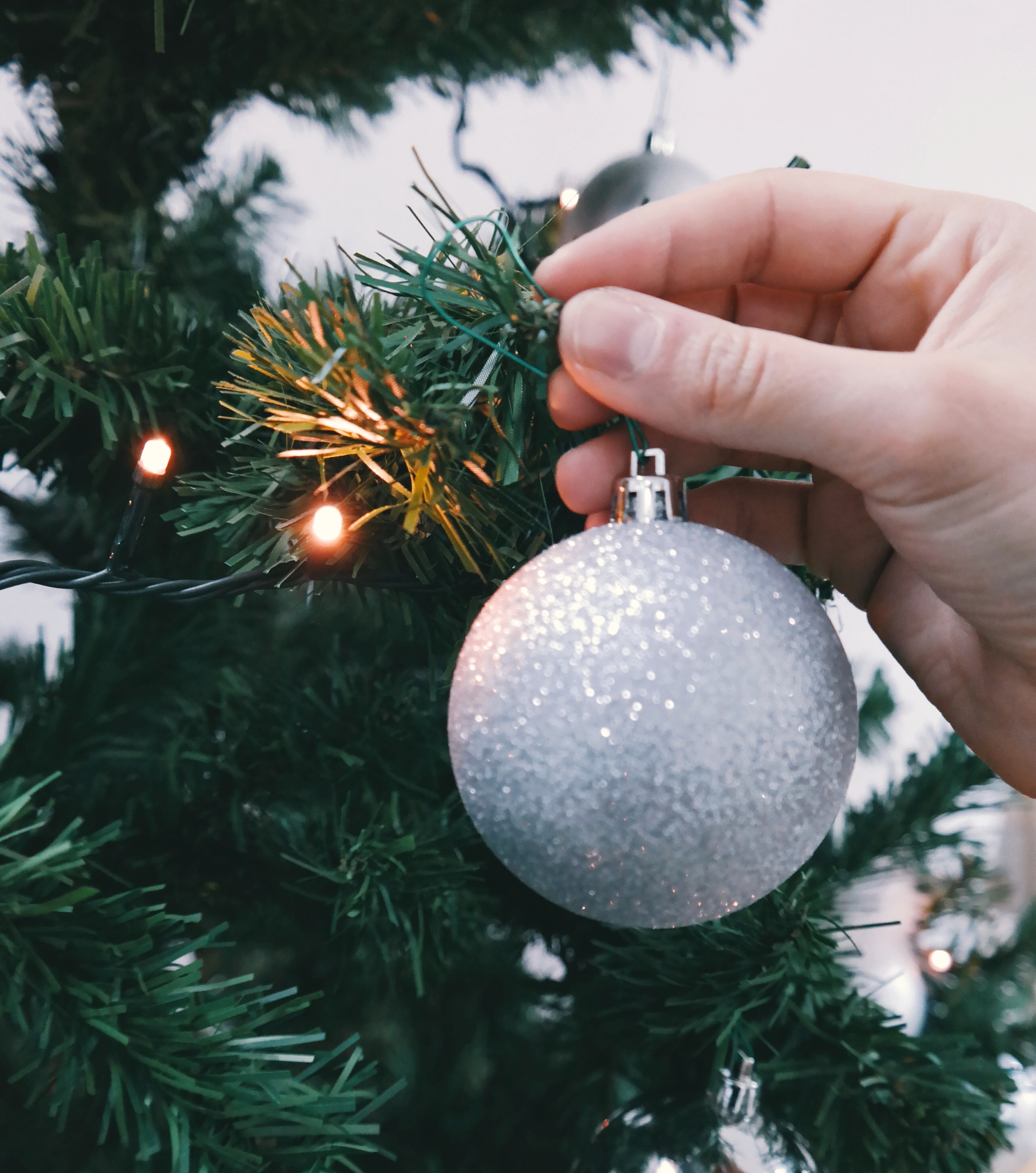silver christmas ball being hold by human's hand