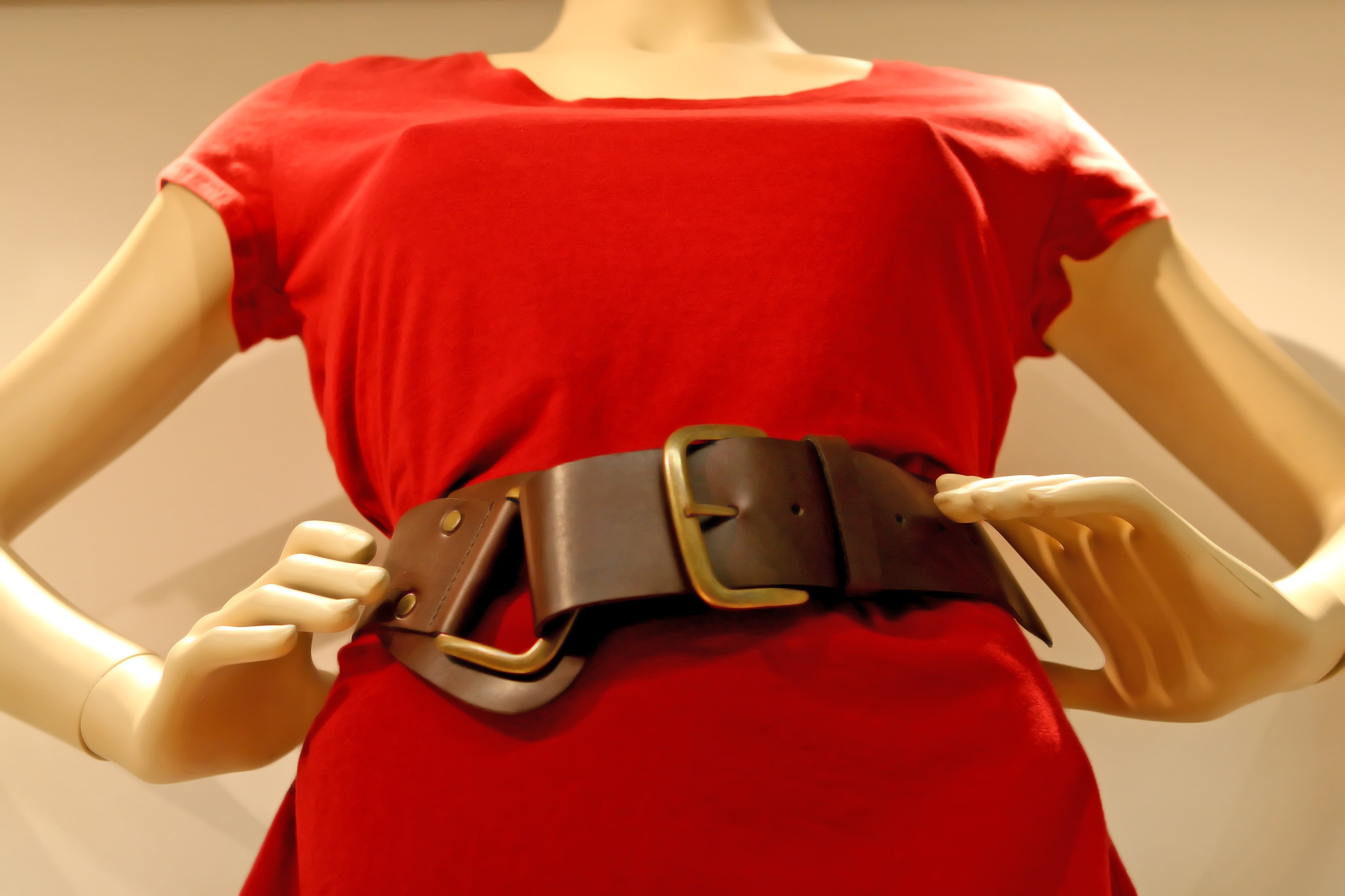 woman mannequin in red cap sleeve dress and brown leather waist belt