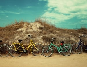 four bicycles leaning on small mountain under white and blue sky thumbnail