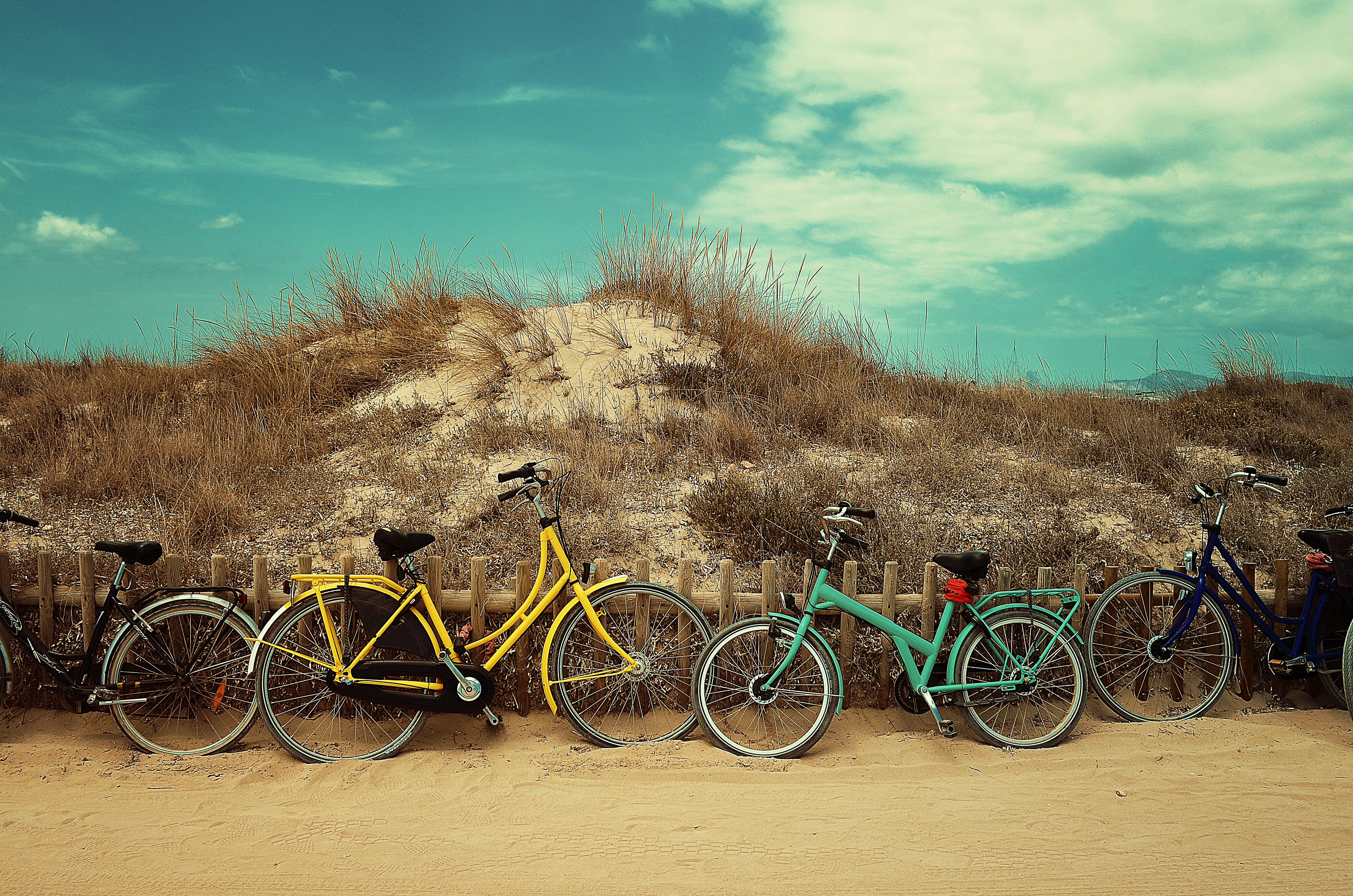 four bicycles leaning on small mountain under white and blue sky