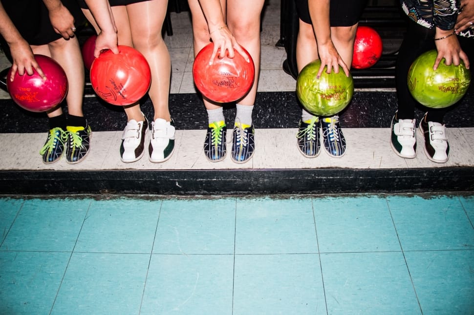 five people standing holding bowling ball near their feet preview