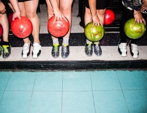 five people standing holding bowling ball near their feet thumbnail