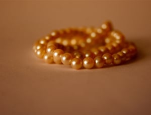 orange pearl necklace on brown concrete surface thumbnail