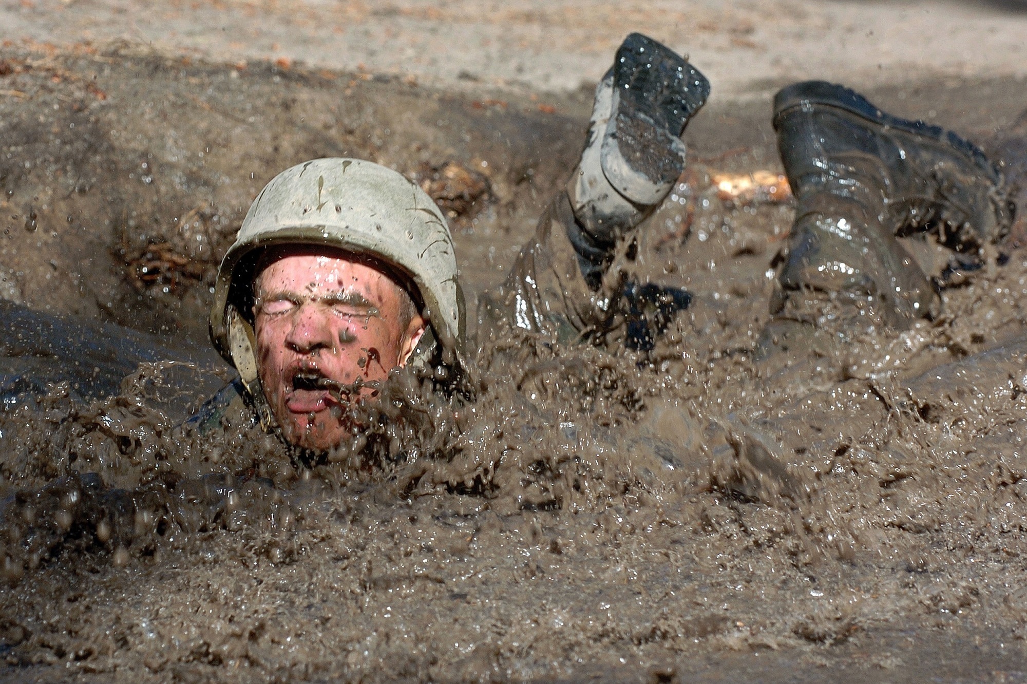 man with helmet dive in the mud during day time